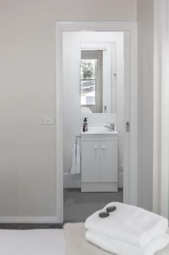 a white bathroom with a sink and a mirror at Gangurru in Myrtleford