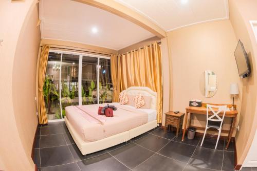 a bedroom with a bed and a desk and a window at Aen Guy Boutique Hotel in Sukhothai