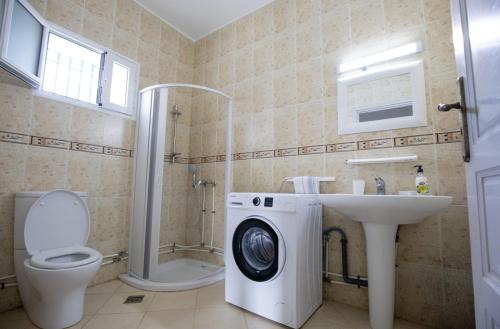 a bathroom with a toilet a sink and a washing machine at Villa Aura in Ouled Yaneg