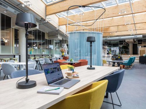 a laptop on a table with chairs in a cafeteria at ibis Styles Delft City Centre in Delft
