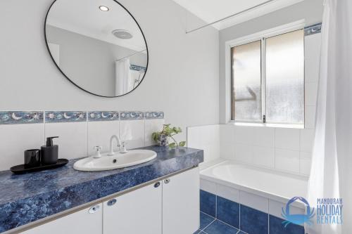 a bathroom with a sink and a tub and a mirror at Mandurah Poolside Retreat in Coodanup