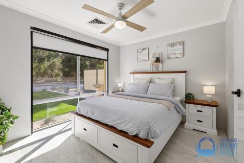 a bedroom with a bed and a large window at Mandurah Poolside Retreat in Coodanup