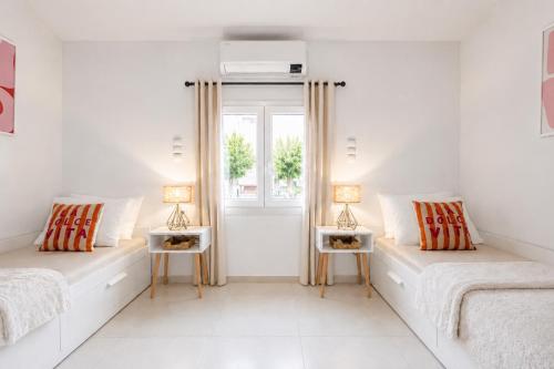 two beds in a white room with two lamps on tables at Seaside Breeze Villa - Beachfront, Private Pool, BBQ in Agia Pelagia