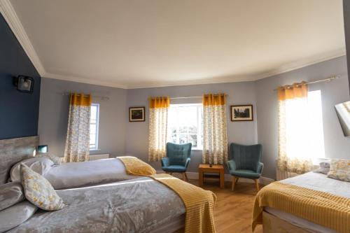 a bedroom with two beds and two chairs and windows at Kerrigan's B&B in Mullingar