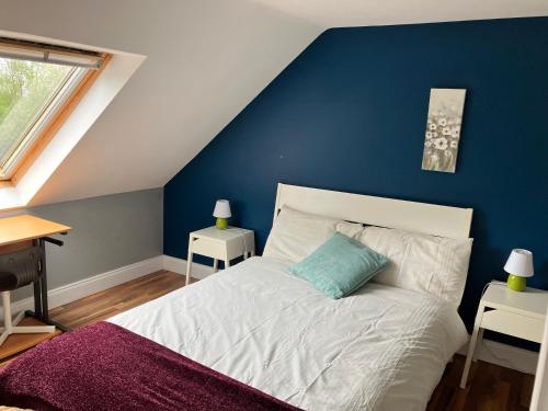 a bedroom with a white bed with a blue wall at Silver Birch House in Laune Bridge