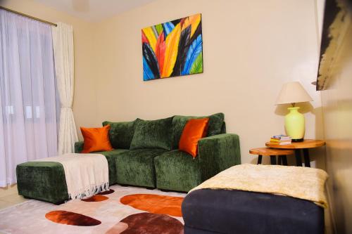 a living room with a green couch and a painting at Savannah suites Bel-Air in Gilgil