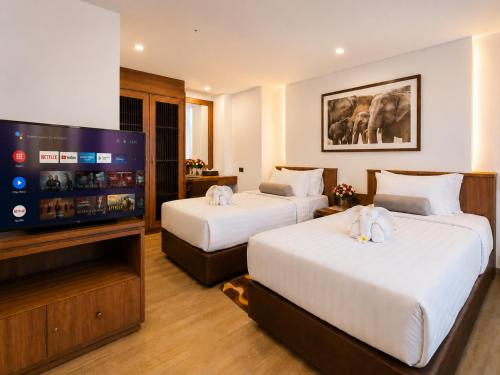 a hotel room with two beds and a flat screen tv at Aiyara Palace in North Pattaya