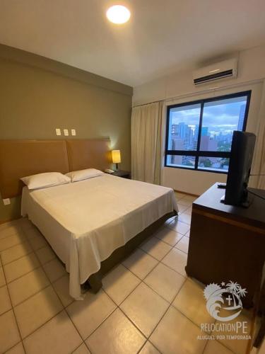 a bedroom with a bed and a television and a window at Flat no Condomínio Metrópolis - Ilha do Leite in Recife