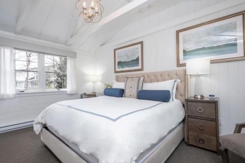 a white bedroom with a large bed and a chandelier at Boothbay Harbor Oceanside Inn in Boothbay Harbor