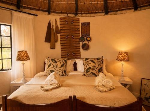 a bedroom with a large bed with towels on it at The Thatched Hideaway on Stanmore farm in Nottingham Road
