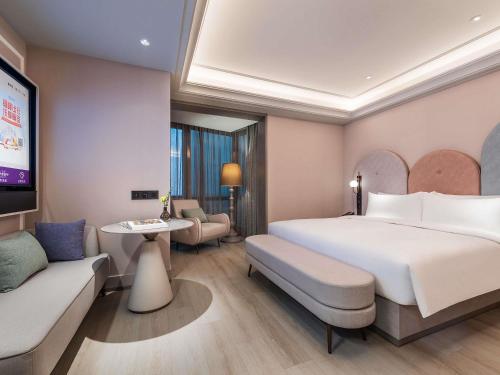 a hotel room with a large bed and a tv at Mercure Ningbo Yinzhou in Ningbo