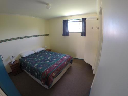 a small bedroom with a bed and a window at Opotiki Holiday Park in Opotiki