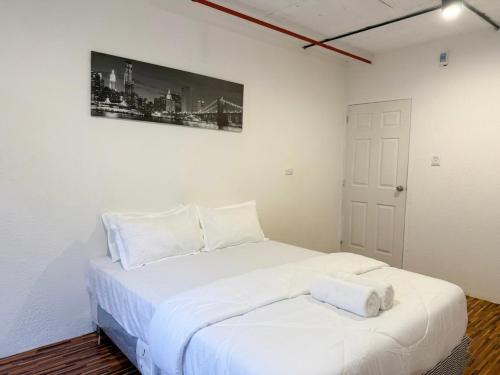 ein weißes Bett in einem Zimmer mit einem Bild an der Wand in der Unterkunft KINBOSHI Inn in Bangkok