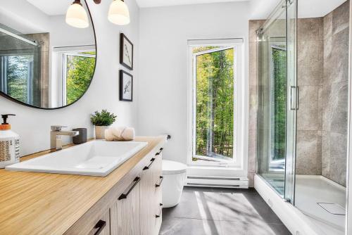 a bathroom with a tub and a sink and a mirror at La Trêve Mont Tremblant in La Conception