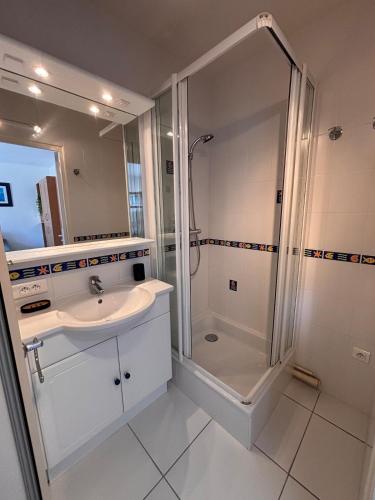 a white bathroom with a shower and a sink at Ti Gon - Le Cabanon Baulois in La Baule
