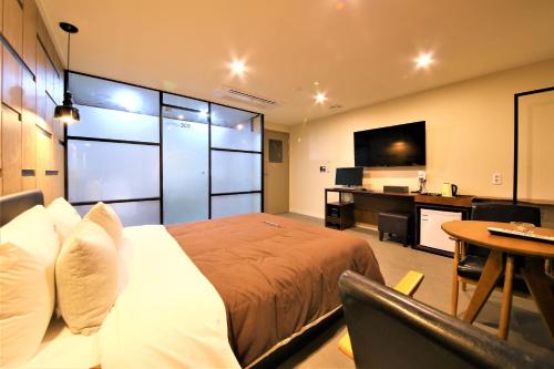 a bedroom with a bed and a desk and a television at Busan Station Dino Hotel in Busan