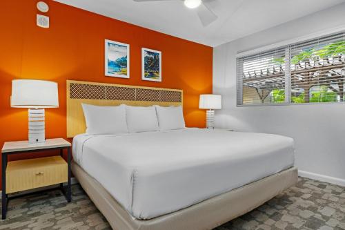 a large bed in a room with an orange wall at WorldMark Kihei in Kihei