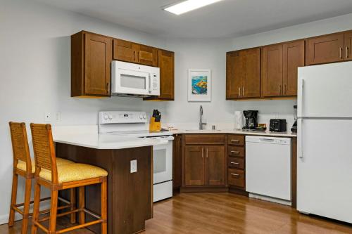 a kitchen with white appliances and wooden cabinets at WorldMark Kihei in Kihei