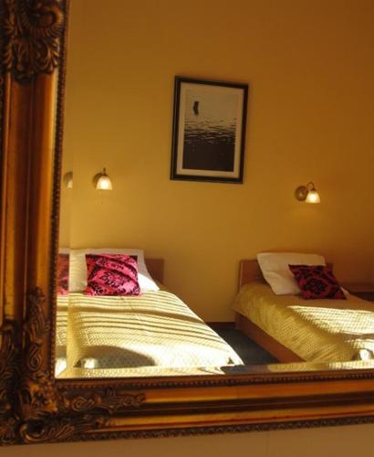 a reflection of a bedroom with two beds in a mirror at Noclegi Apro in Gdańsk