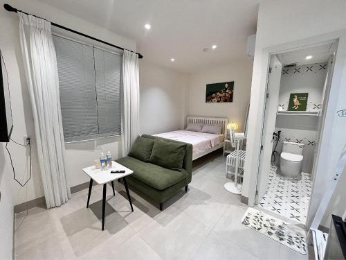 a small room with a bed and a green chair at Cỏ Lá Homestay in Danang