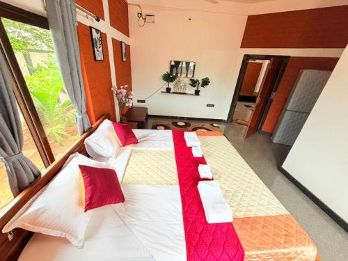 a bedroom with two beds with red pillows at JayKay Resort in Pūrnānkuppam