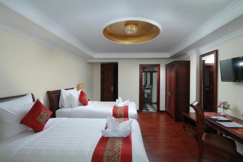 a hotel room with two beds and a desk at Phasouk Vien Chantra Hotel in Vientiane