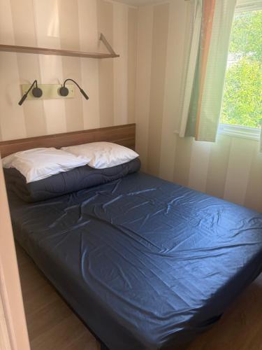 a bed in a room with a blue blanket and a window at camping des iscles 167 in La Roque-dʼAnthéron