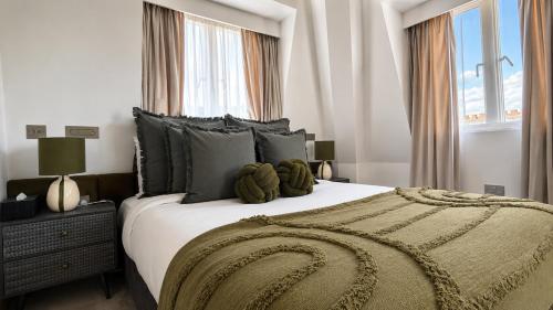a white bedroom with a large bed with pillows at The Apex Penthouse, Hyde Park in London