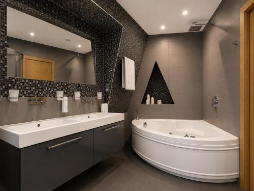 a bathroom with a large tub and a large mirror at The Apex Penthouse, Hyde Park in London