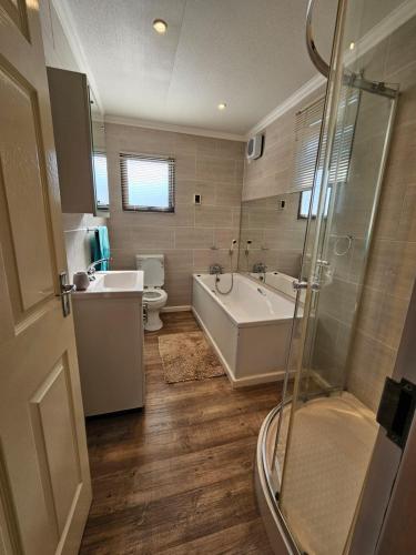a bathroom with a tub and a toilet and a shower at THE PONT port Edward UNIT 1 in Port Edward