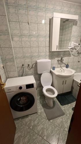 a bathroom with a toilet and a washing machine in it at Paradiso 5 in Bratunac