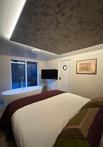 a bedroom with a large bed and a bath tub at De Waterlodge - Uniek verblijf aan het water in Franeker