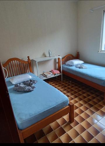 two twin beds in a room with a tiled floor at Casa Areal in Araruama