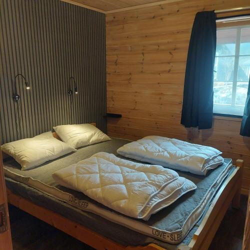 two twin beds in a room with wooden walls at Cabin in Hjelmeland in Hjelmeland