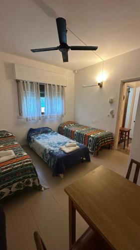 a room with three beds and a ceiling fan at Hotel Maresias in Villa Gesell