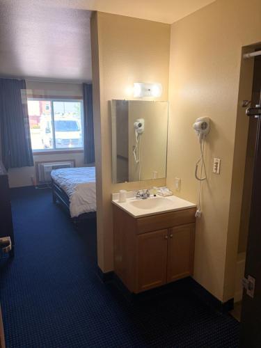 a bathroom with a sink and a mirror and a bed at East Grand Inn Grand Forks ND I 29 in East Grand Forks