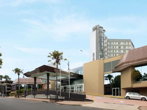a building with a car parked in front of it at Mercure Sydney Bankstown in Bankstown