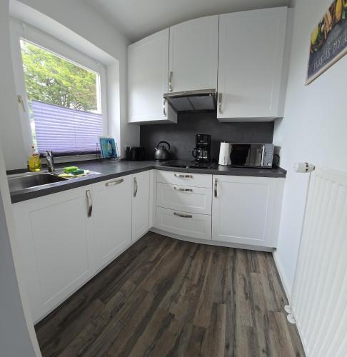 a kitchen with white cabinets and a sink and a window at Fiete in Marienleuchte