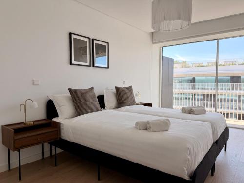 a bedroom with a large bed and a large window at Nooba Barreiro Apartment in Barreiro
