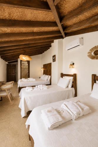 a room with three beds with white sheets at NURİYE ALACATI in Alaçatı