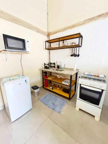 a kitchen with a stove and a refrigerator at Chalés & Suítes Praia Barequeçaba I Cozinha Compacta in São Sebastião