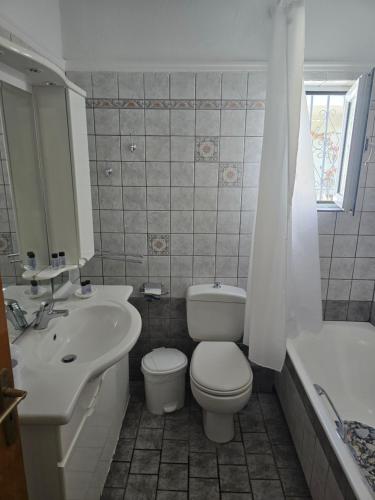 a bathroom with a toilet and a sink and a tub at La Casa Tzortzina in Kokkino Nero