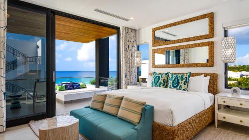 a bedroom with a bed and a balcony with the ocean at Tranquility Beach Anguilla Resort in Meads Bay