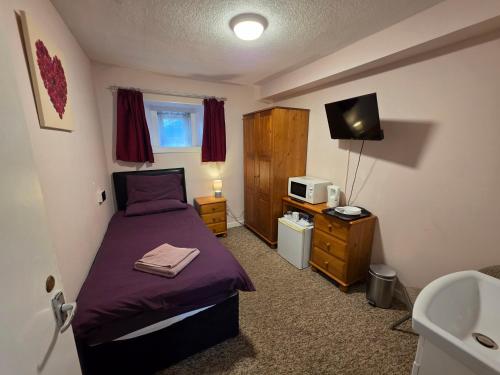 a small bedroom with a bed and a sink at Station View Guest House in Dyce