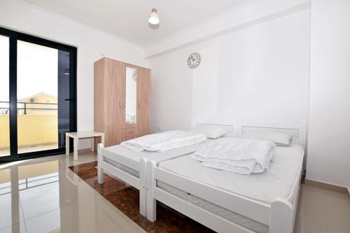 a white bedroom with two beds and a window at Jednosoban stan Milinic in Herceg-Novi