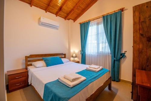 a bedroom with a bed and a window with blue curtains at Villa Masal in Kayakoy