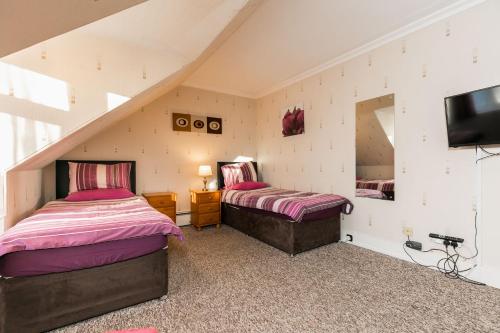 a attic bedroom with two beds and a tv at Station View Guest House in Dyce