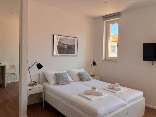 a white bed in a white bedroom with a window at Ridzak Riva Rooms in Mali Lošinj