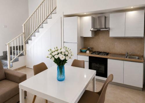 a vase of flowers on a white table in a kitchen at Dimora Azzurra in Pachino