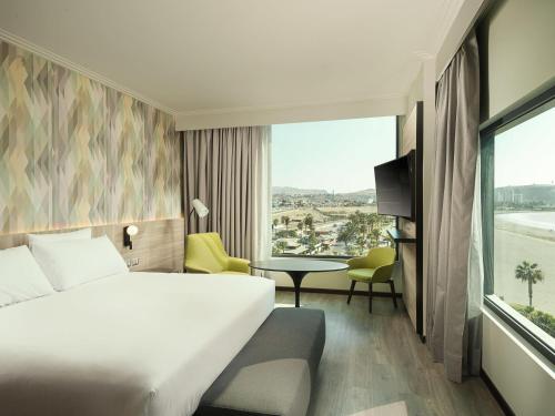 a hotel room with a bed and a large window at Novotel Arica in Arica